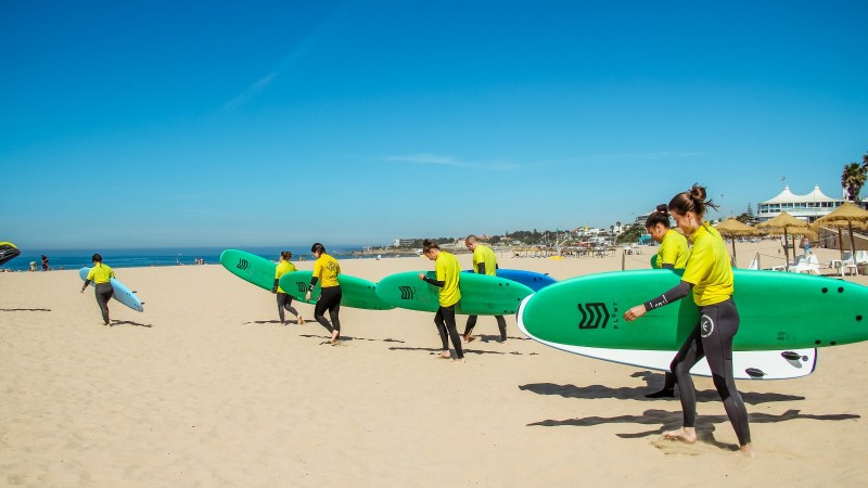 a group of people walking on a beach holding a surfboard
