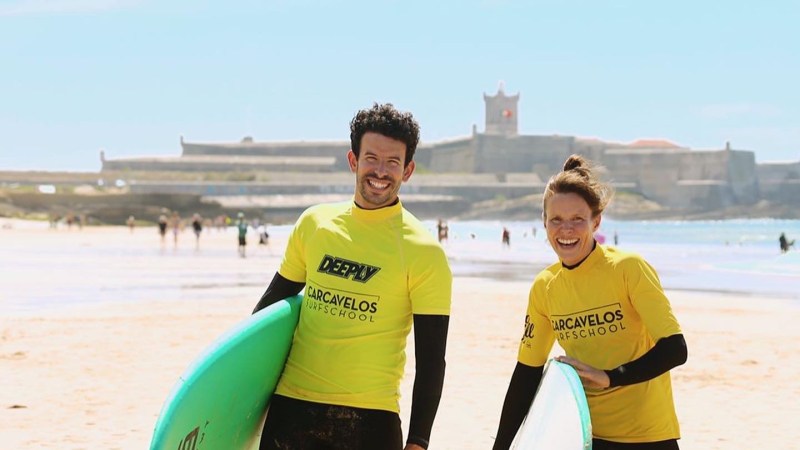 Jesus Torres et al. standing on a beach holding a surfboard