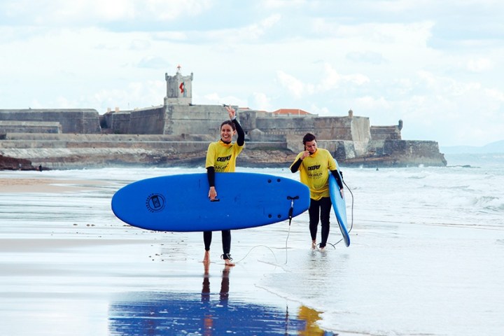 a person carrying a surf board on a body of water