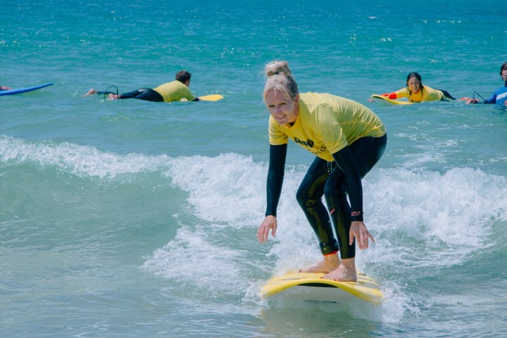 a man and a woman riding a wave on a surfboard in the ocean