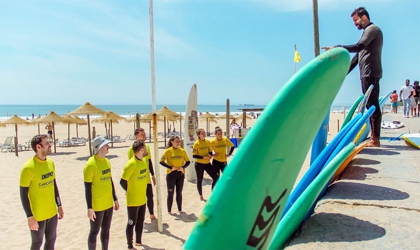 dicasaula a group of people standing on a beach holding a surfboard