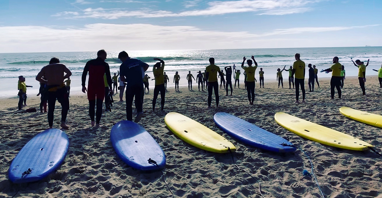 a group of people on a beach holding a surfboard
